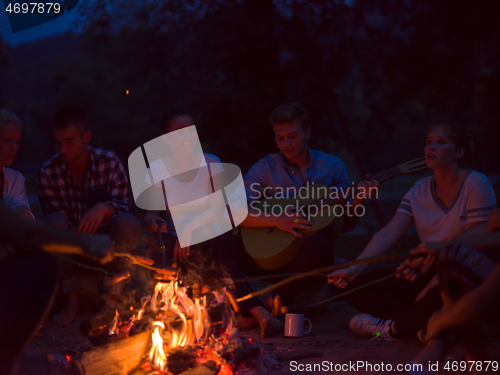 Image of young friends relaxing around campfire