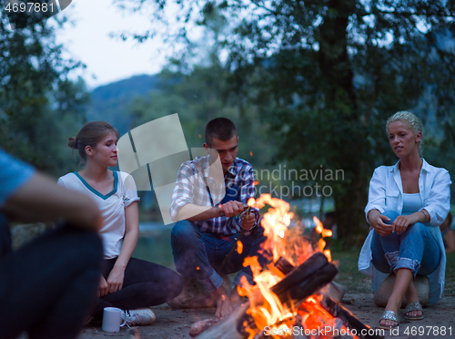 Image of young friends relaxing around campfire