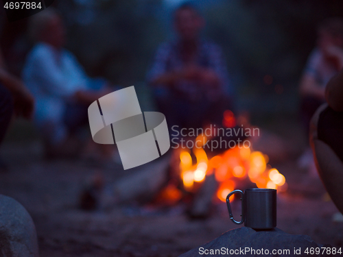 Image of young friends relaxing around campfire