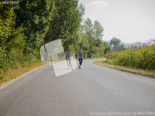 Image of young couple jogging along a country road