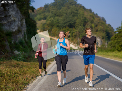 Image of young people jogging on country road