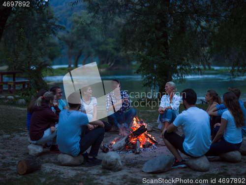 Image of young friends relaxing around campfire