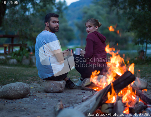 Image of couple sitting around the campfire at evening