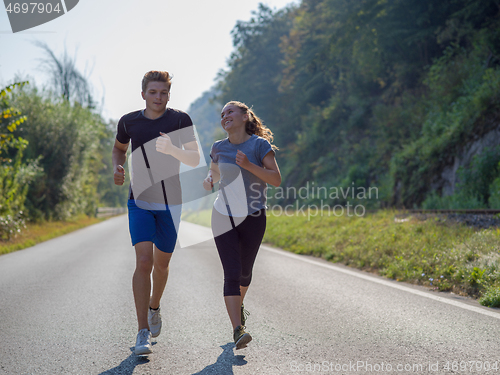 Image of young couple jogging along a country road