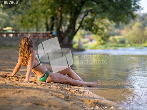 Image of girl in a green bikini relaxing on the riverbank