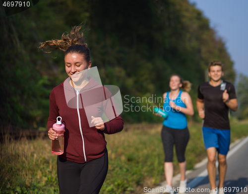 Image of young people jogging on country road