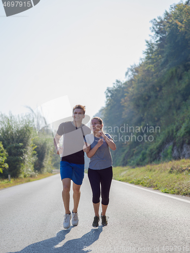 Image of young couple jogging along a country road