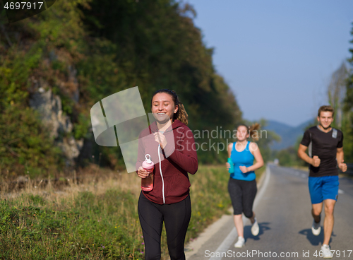 Image of young people jogging on country road