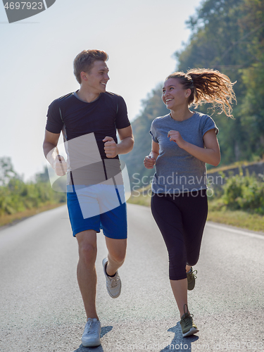 Image of young couple jogging along a country road