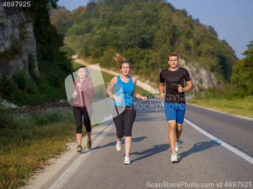 Image of young people jogging on country road