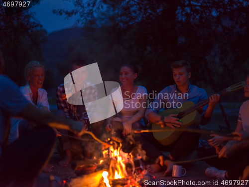 Image of young friends relaxing around campfire