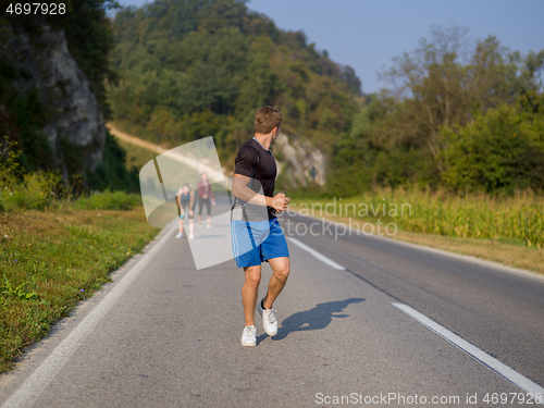 Image of young people jogging on country road