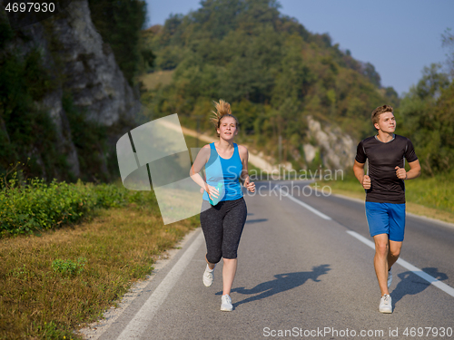 Image of young couple jogging along a country road