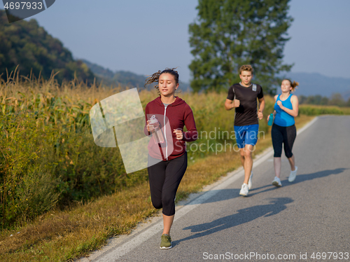 Image of young people jogging on country road