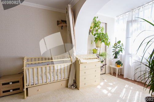 Image of A newborn baby\'s crib and a changing table stand at the entrance to the glazed balcony