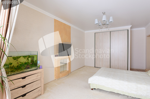 Image of Interior of a spacious bedroom, stands an aquarium, TV and wardrobe