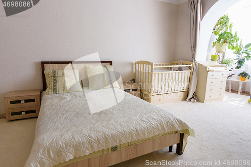 Image of Bedroom interior, adult bed, newborn crib and changing table nearby