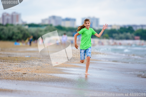 Image of A girl of ten runs joyfully along the seashore