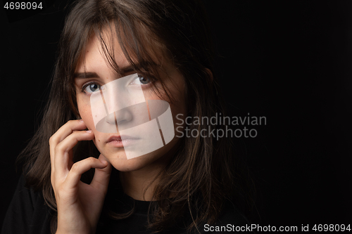Image of Portrait of a beautiful girl with a thoughtful look on a black background