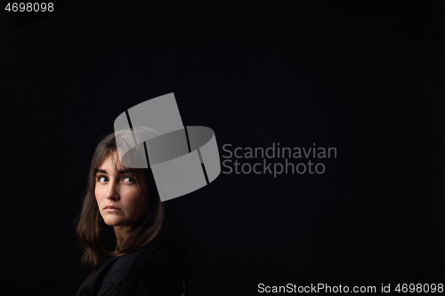 Image of The girl looks at the empty space around her, black background