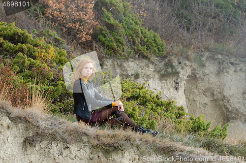 Image of Beautiful girl in autumn clothes sits in a picturesque place