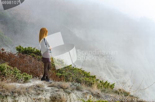 Image of The girl watches the foggy sunrise in the mountains