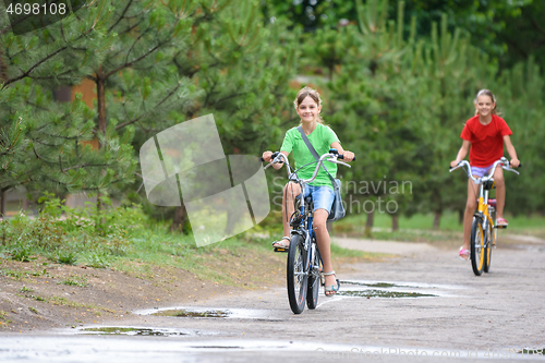 Image of Two girls ride a bike on a rainy warm day