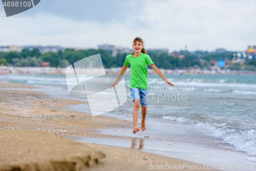 Image of The girl runs happily along the sea coast