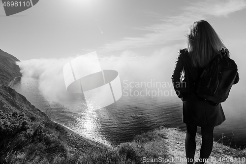 Image of Girl watching from the mountain for the fog over the sea, black and white photography