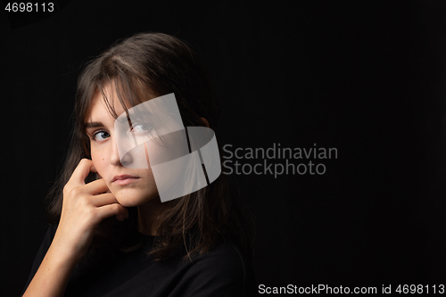 Image of Art portrait of sixteen year old teenage girl in dark clothes on black background