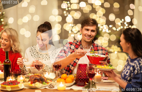 Image of happy friends having christmas dinner at home