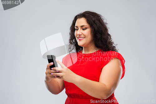 Image of happy woman in red dress using smartphone