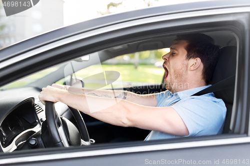 Image of tired sleepy man or driver driving car and yawning