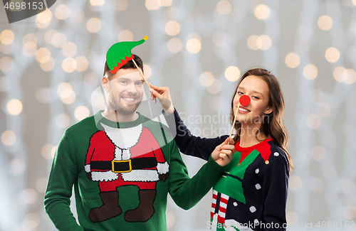 Image of couple with christmas party props in ugly sweaters