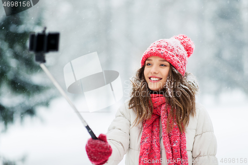 Image of young woman taking selfie by monopod in winter