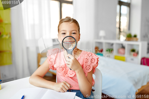 Image of student girl with magnifier and notebook at home