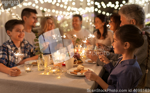 Image of family with sparklers having dinner party at home