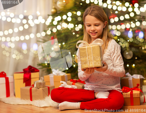 Image of smiling girl with christmas gift at home