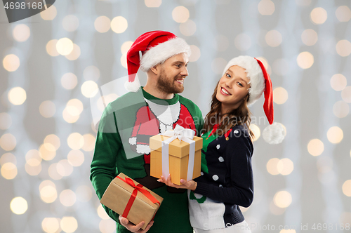 Image of happy couple in christmas sweaters with gifts