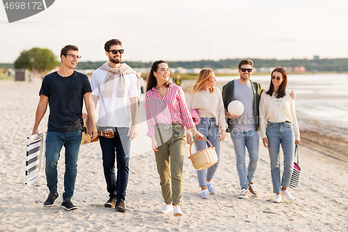 Image of happy friends walking along summer beach