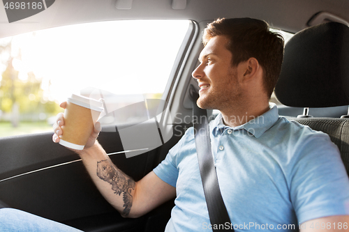 Image of man with takeaway coffee on back seat of taxi car