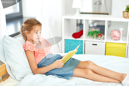 Image of happy little girl reading book at home