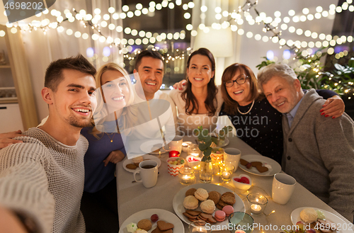 Image of happy family taking selfie at tea party at home