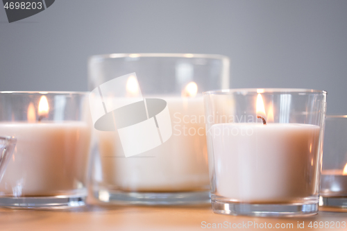 Image of burning white fragrance candles on wooden table