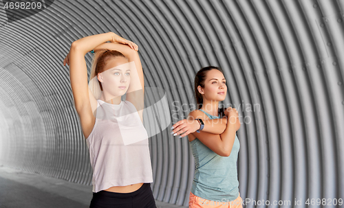 Image of women with fitness trackers stretching outdoors