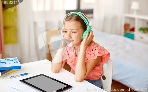 Image of girl in headphones with tablet computer at home