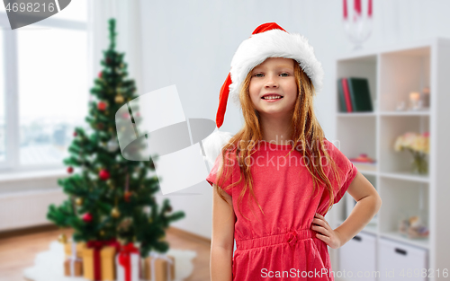 Image of happy red haired girl in santa helper hat at home