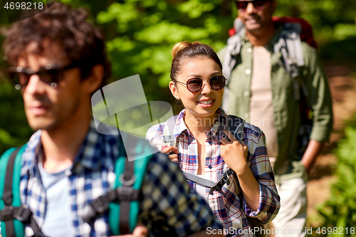 Image of group of friends with backpacks hiking in forest