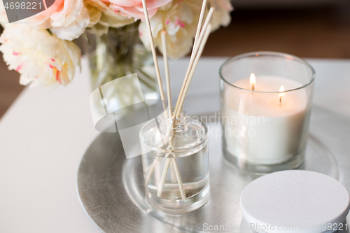 Image of aroma reed diffuser, candle and flowers on table