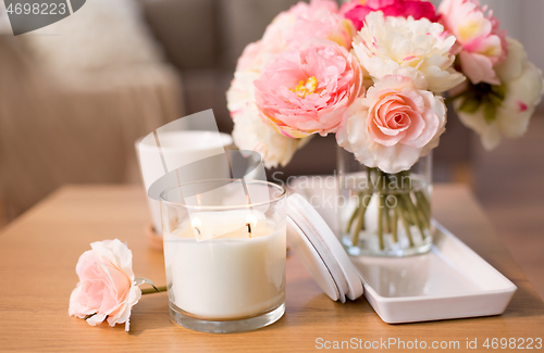 Image of burning candle and flower bunch on table at home
